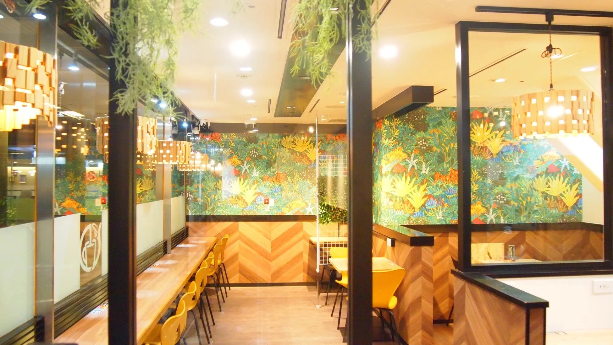 植物柄の壁紙と黄色の椅子があるカフェ