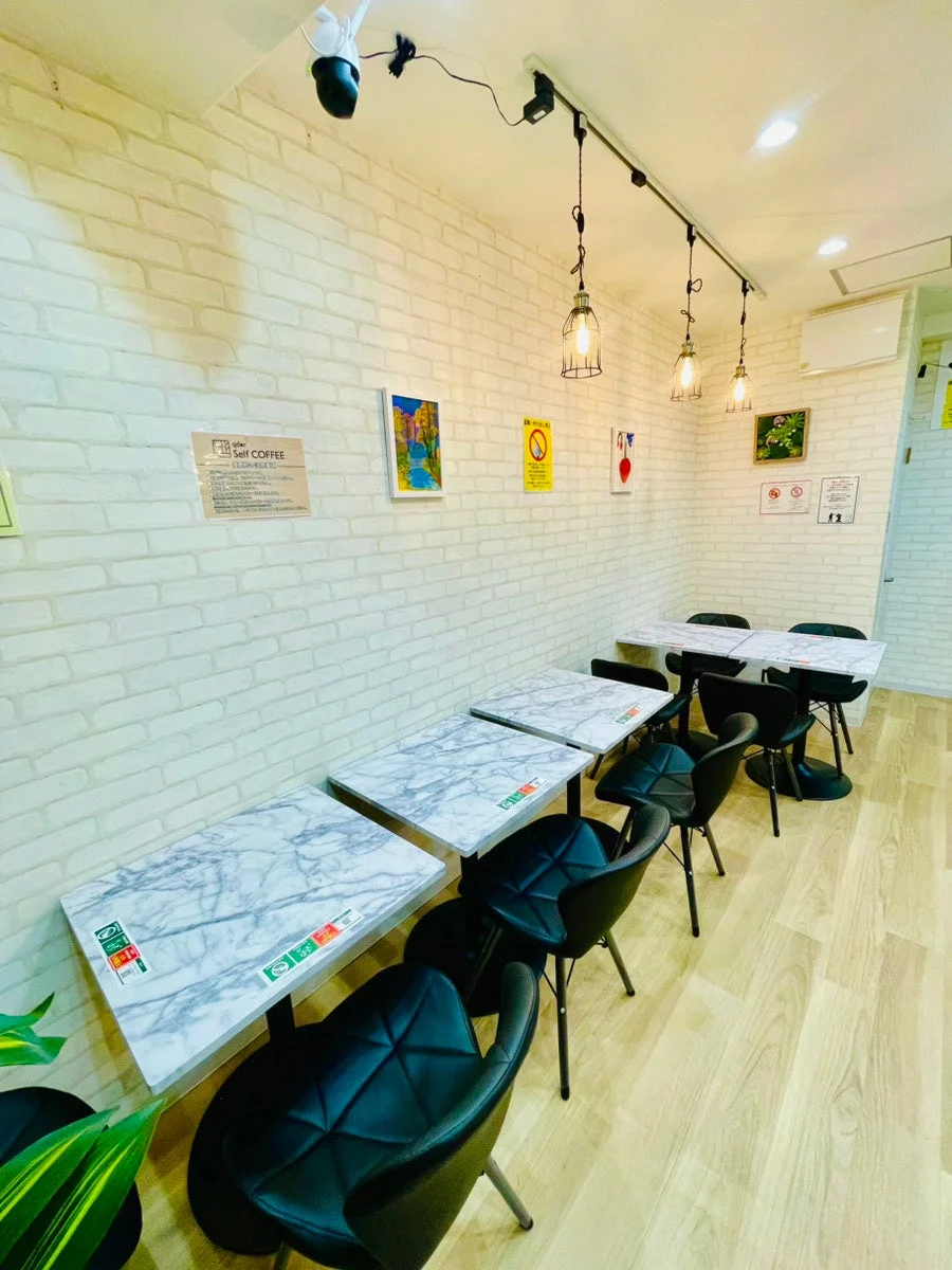 Qder self cafe 針中野駅前店の店内の様子。白のレンガ調の壁と大理石調のテーブルが並び、モダンな雰囲気。