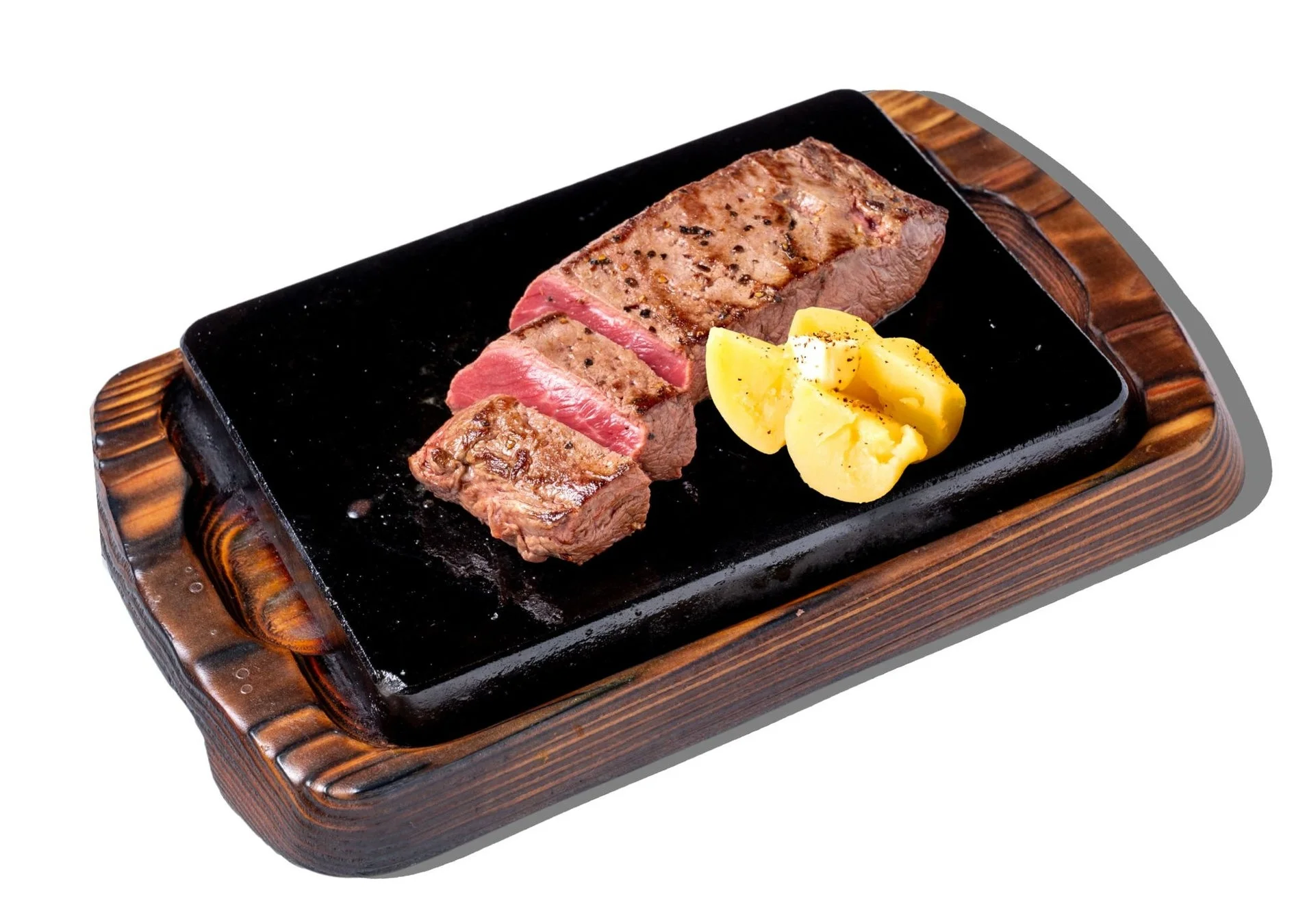 熱々の鉄板に盛り付けられた、適度に焼かれたミディアムレアのステーキと付け合わせのポテト。