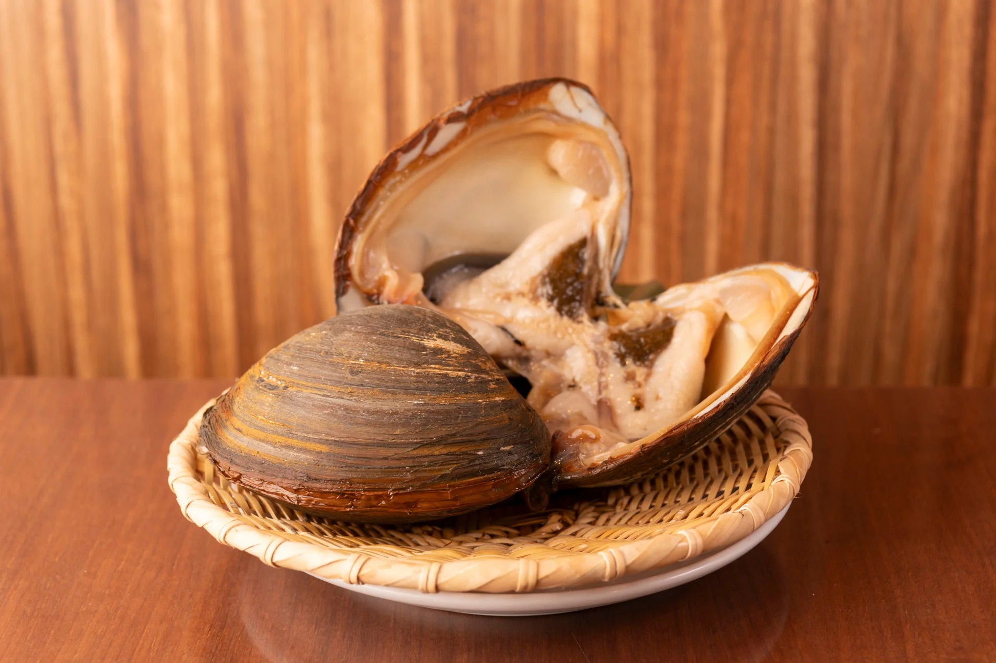籐の皿に盛られた新鮮なハマグリのような大型の二枚貝