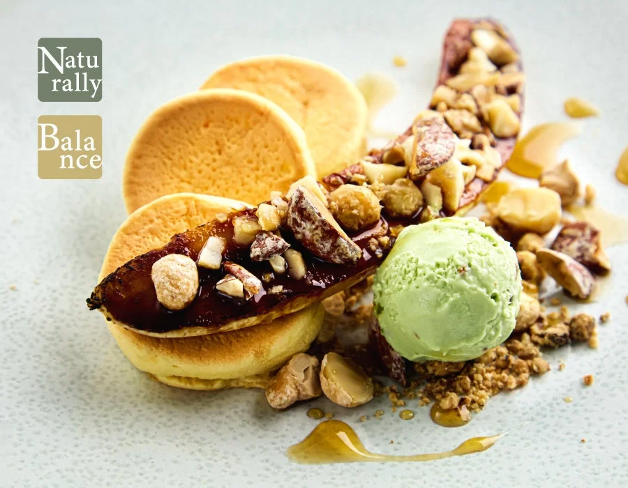 ふかふかのパンケーキに、キャラメリゼされたバナナとナッツが添えられ、鮮やかな緑色のアイスクリームが添えられた、美味しそうなデザート