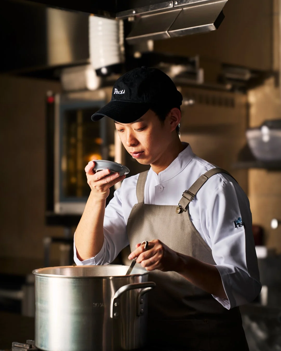 厨房で料理を味見するシェフ