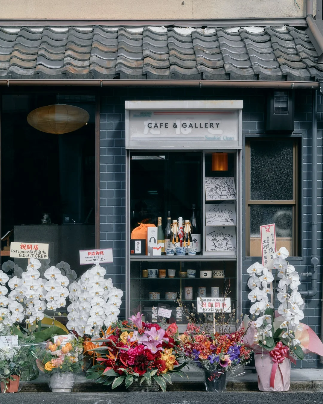 伝統的な瓦屋根の建物に飾られた開店祝いの花々