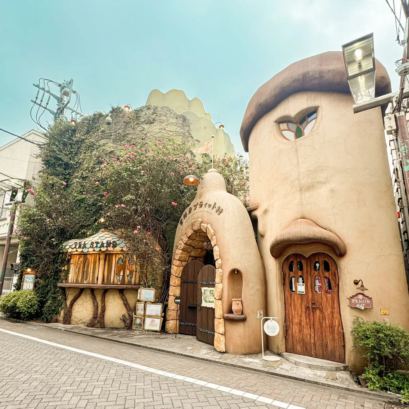 蔦とピンクの花で覆われた、キノコのような形のユニークな建物