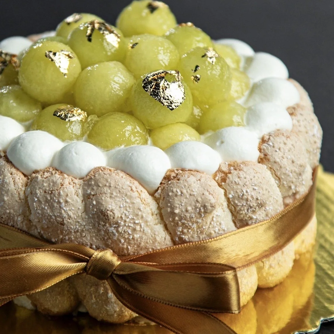 メロンまたはマスカットがたっぷり飾られ、金箔が散りばめられた華やかなシャーロットケーキです。