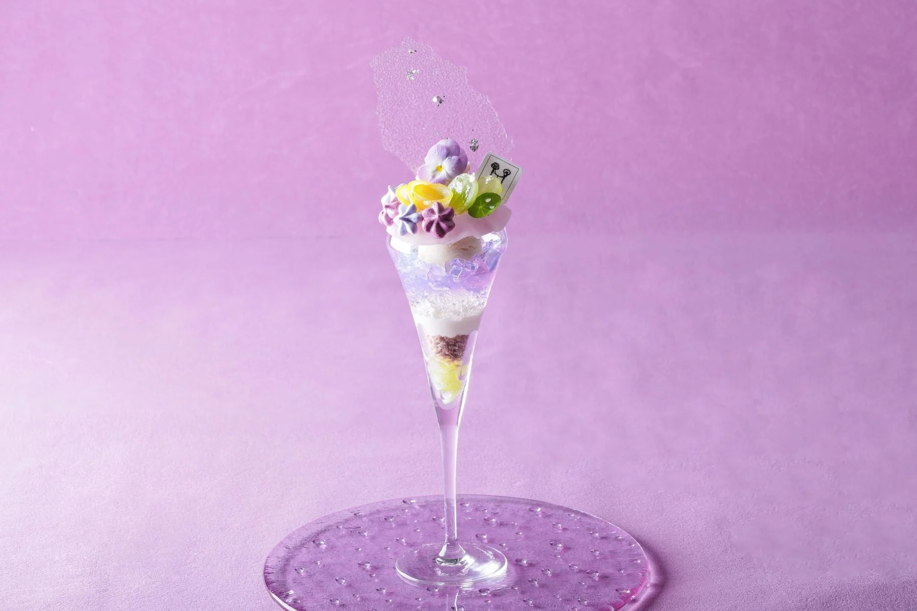 紫色の花やカラフルな飾り付けが美しい、芸術的なパフェ