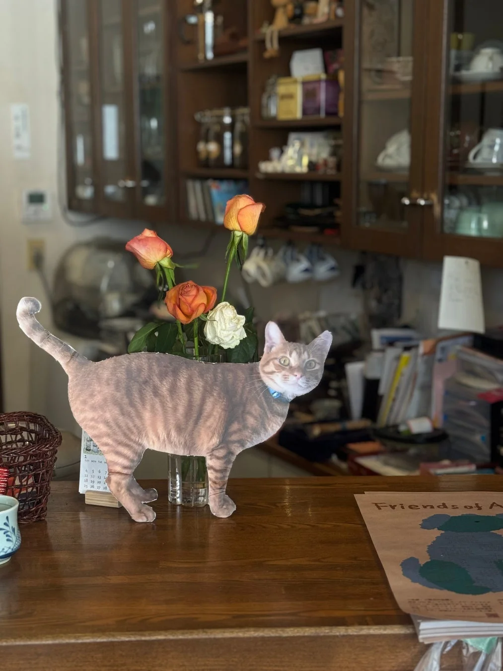 木製のカウンターに猫の置物とバラが生けられた花瓶