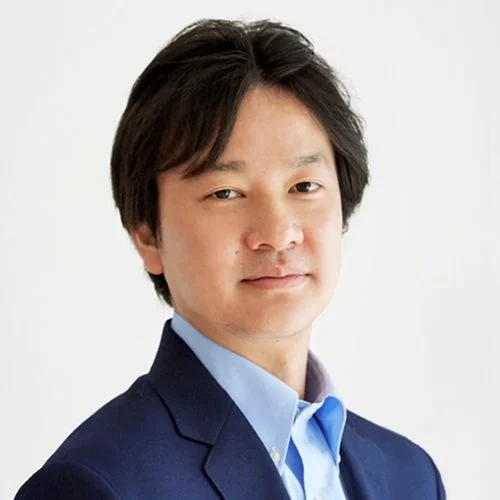 青いシャツと紺色のジャケットを着用したアジア系の男性のプロフェッショナルなポートレート写真です。白い背景で、顔がはっきりと写っています。