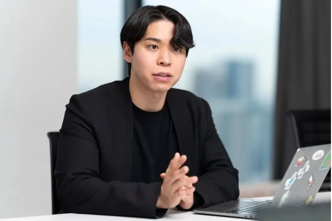 男性がノートPCの前で話す