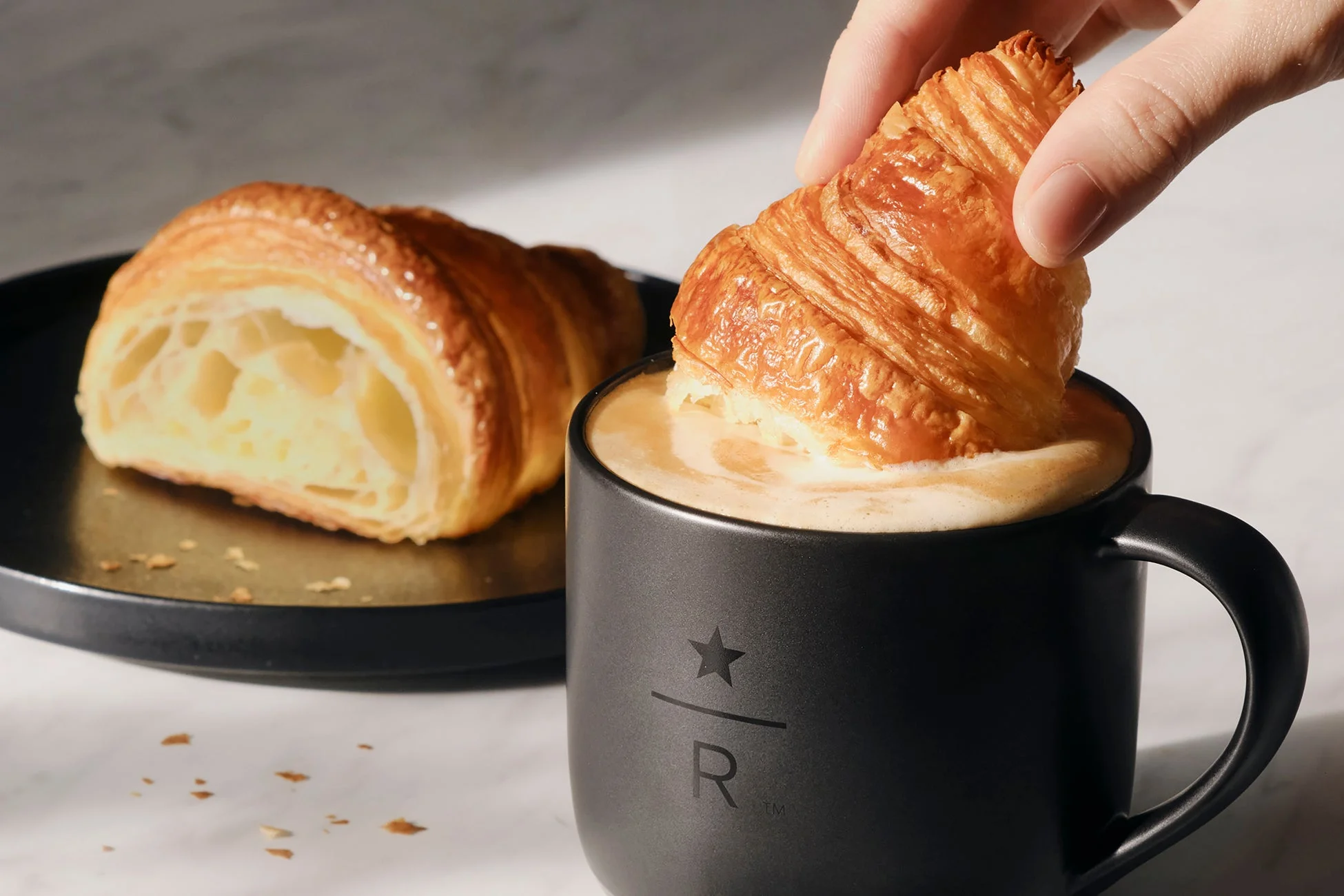 コルネッティをコーヒーにディップする様子