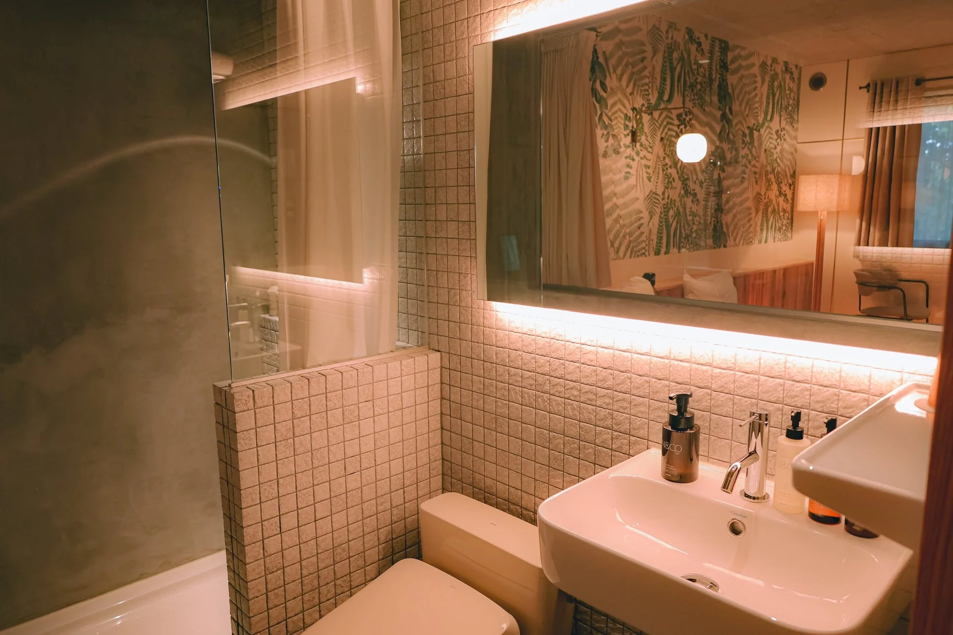 モダンなデザインのバスルームで、洗面台、トイレ、シャワーブースが配されています。