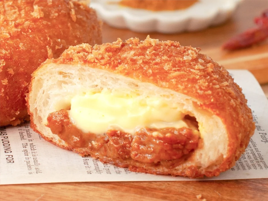 こんがりと揚がったカレーパンが半分にカットされ、中からとろりとしたカレーと白いクリーム（チーズ）が顔をのぞかせている