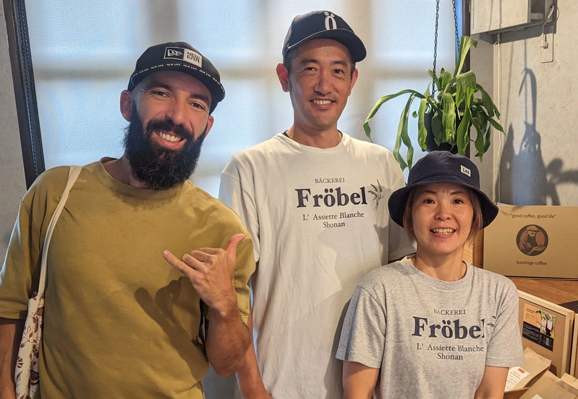 「ベーカリーFröbel」のTシャツを着た2人を含む3人が笑顔でポーズをとっている