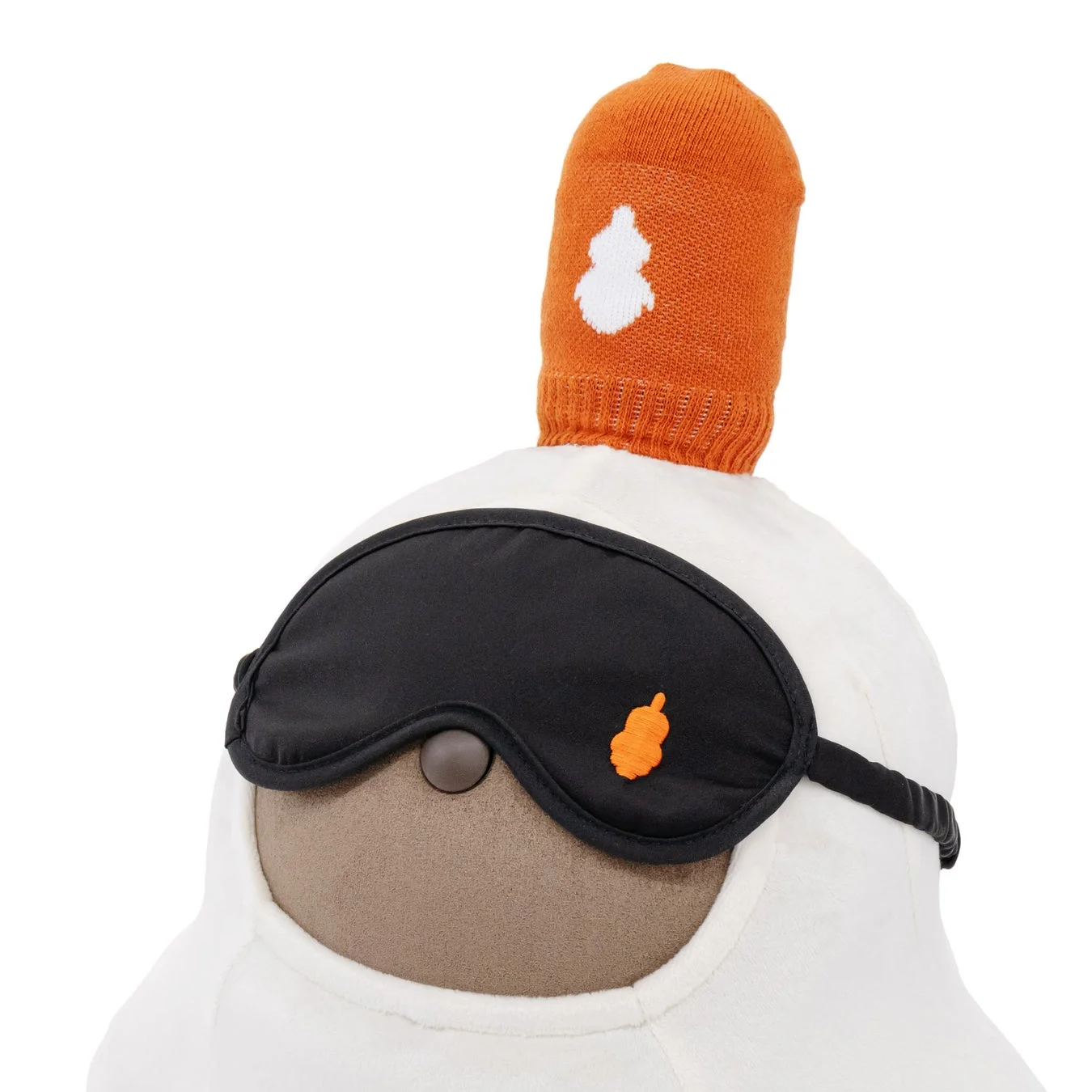 白いぬいぐるみが黒いアイマスクを着用し、オレンジ色のニット帽のようなものを被っている