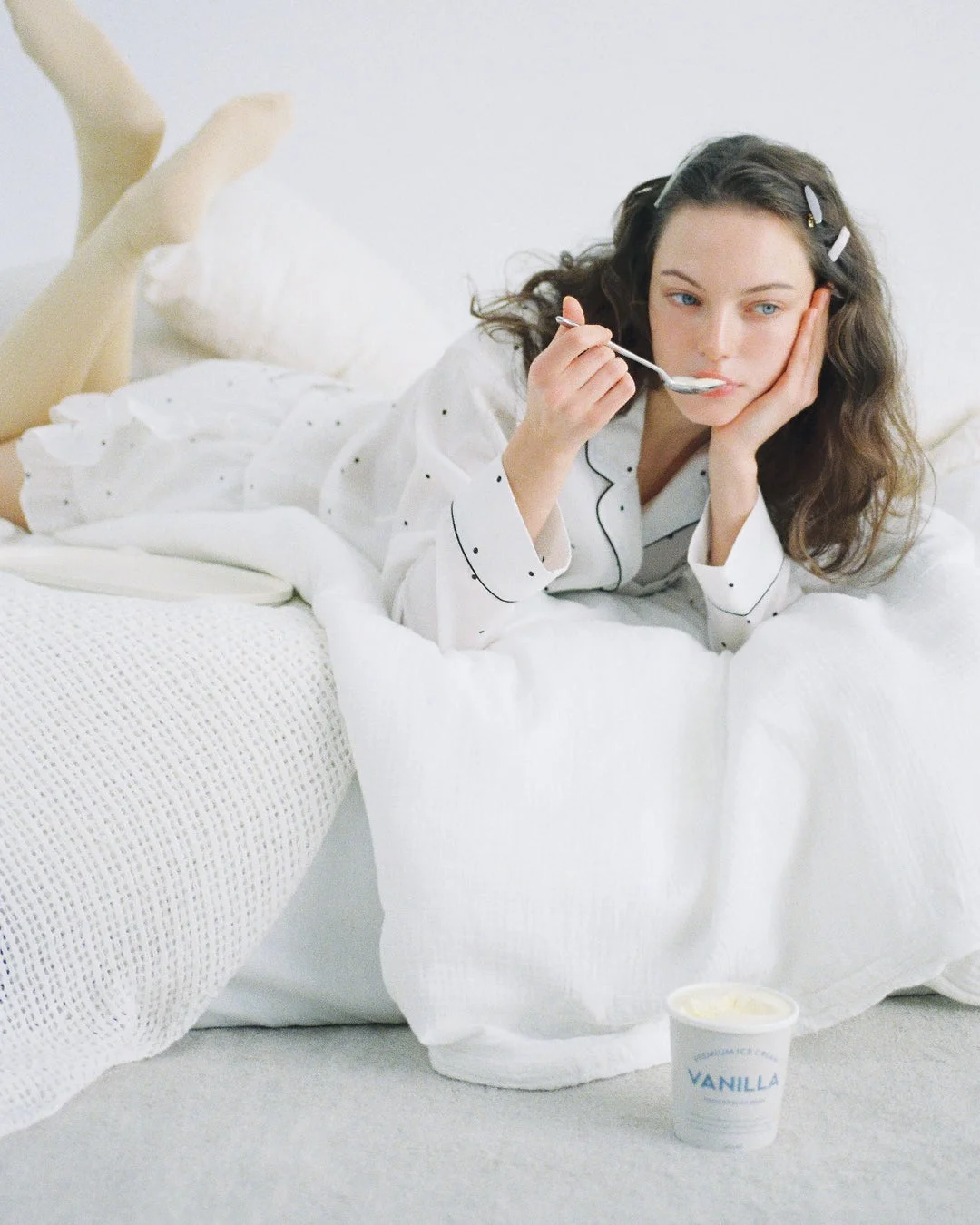 ベッドでアイスクリームを食べるパジャマ姿の女性