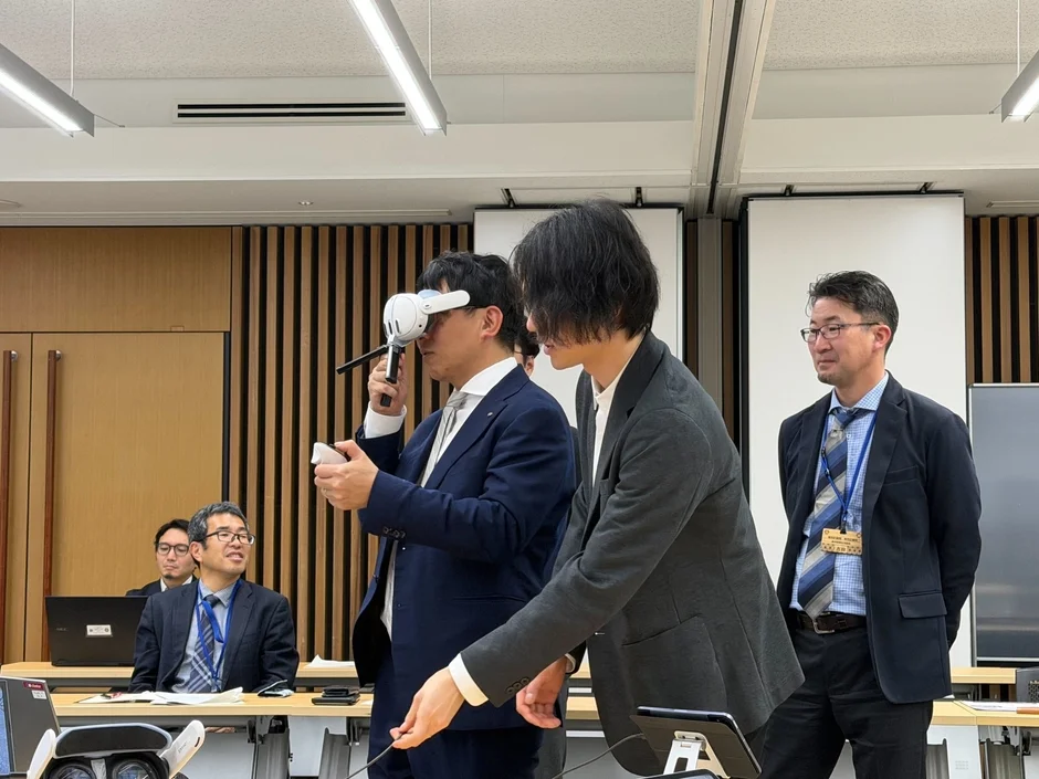 VRヘッドセットを装着した男性がデモンストレーションを行う会議室の様子
