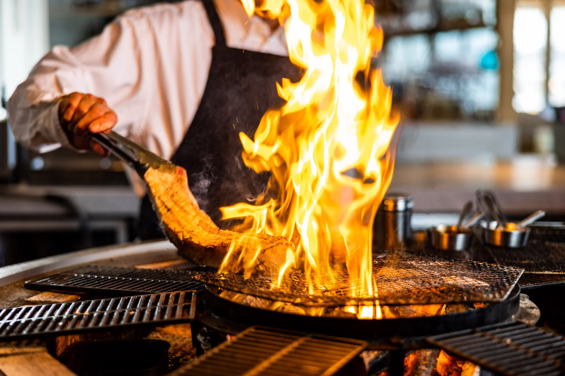 シェフが炎を上げて肉をグリルで調理