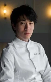 白いコックコートを着用したアジア人男性のポートレートです。