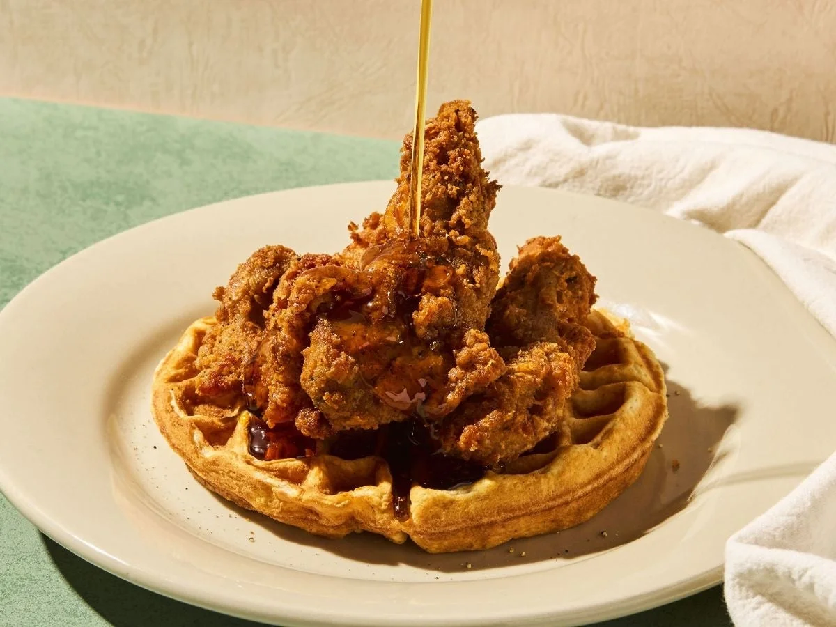 サクサクのフライドチキンが乗ったワッフルに、とろりとしたメープルシロップがかけられている様子を捉えた美味しそうな一枚。甘じょっぱい組み合わせが食欲をそそります。