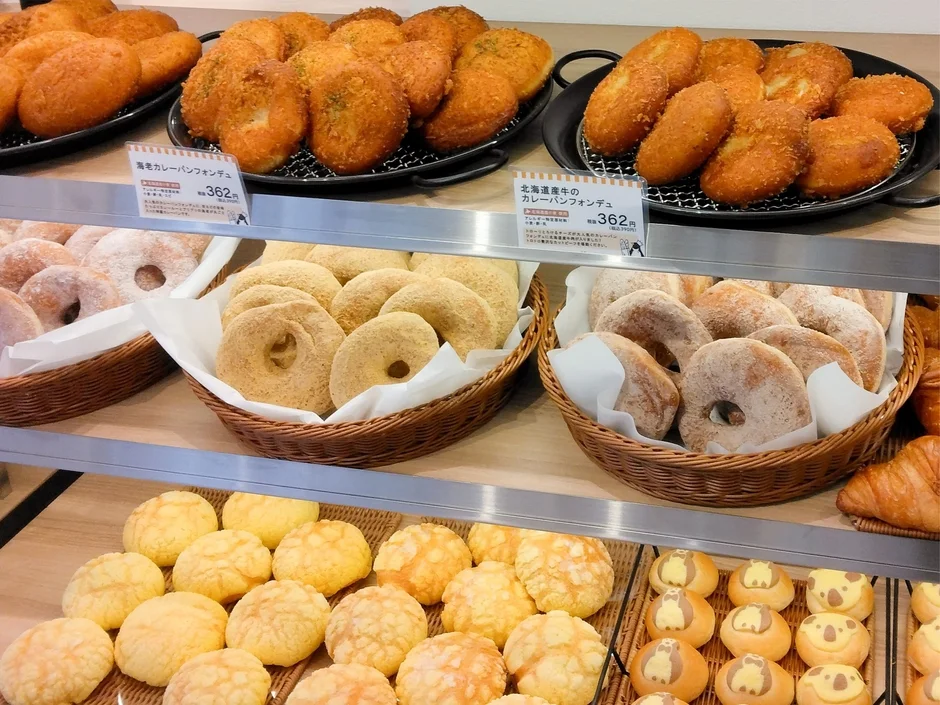 パン屋の陳列棚に様々な種類のパンが並べられています