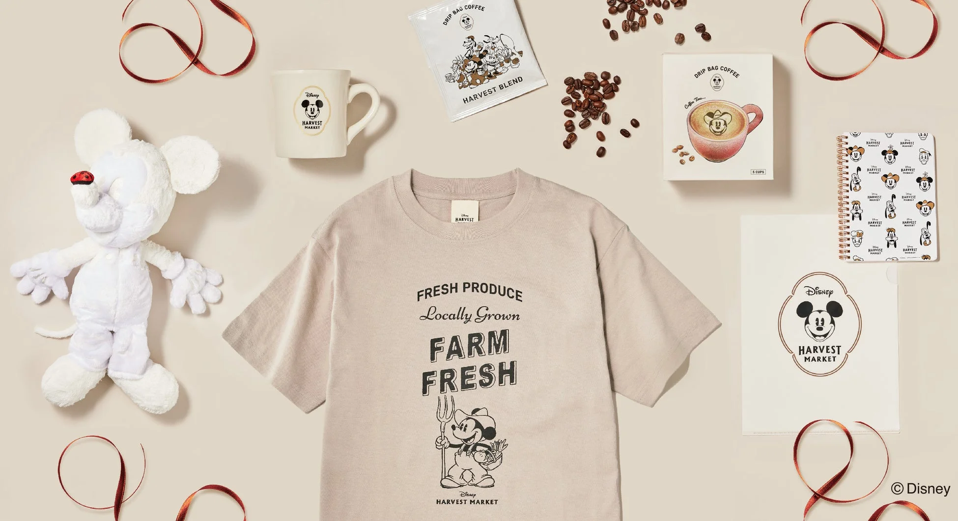 ディズニーの「HARVEST MARKET」シリーズの様々な商品が並べられた画像です。ミッキーマウスのぬいぐるみ、Tシャツ、マグカップ、ドリップコーヒー、ノート、クリアファイルなどが含まれ、農園や収穫をテーマにしたデザインが特徴です。