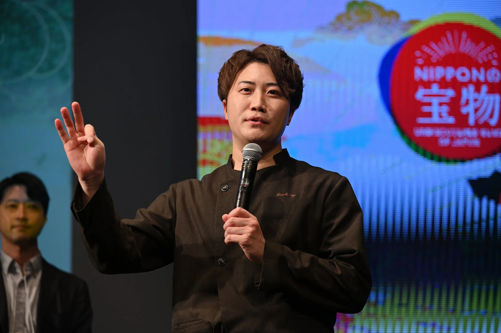 ステージでプレゼンテーションを行う男性