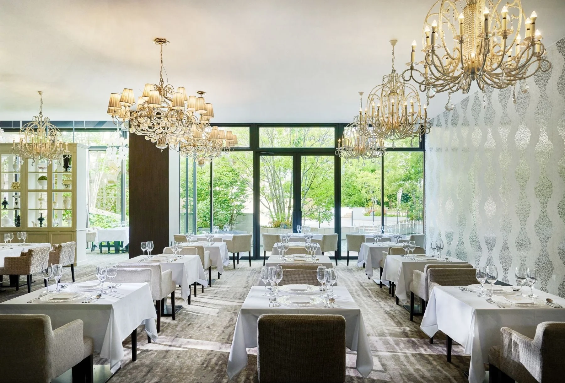 豪華なシャンデリアが複数吊るされた、エレガントなレストランのダイニングルーム