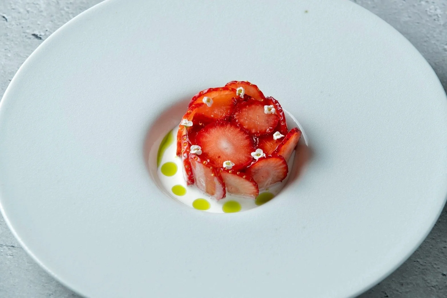 白い深皿に美しく盛り付けられたイチゴのデザート