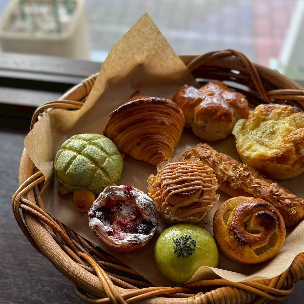 様々な種類のパンやペイストリーが籐のバスケットに美しく盛り付けられている