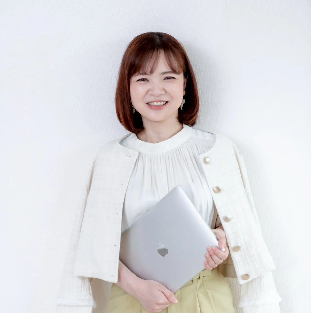 白い背景の前に立つ、笑顔の日本人女性のポートレート