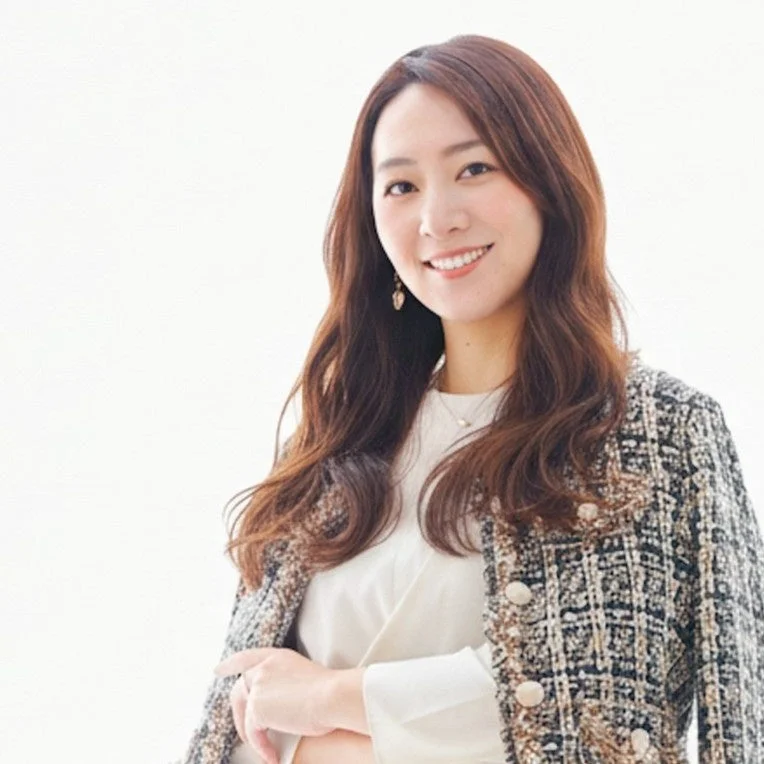 白い背景の前で微笑む、長い茶色の髪の女性のポートレート