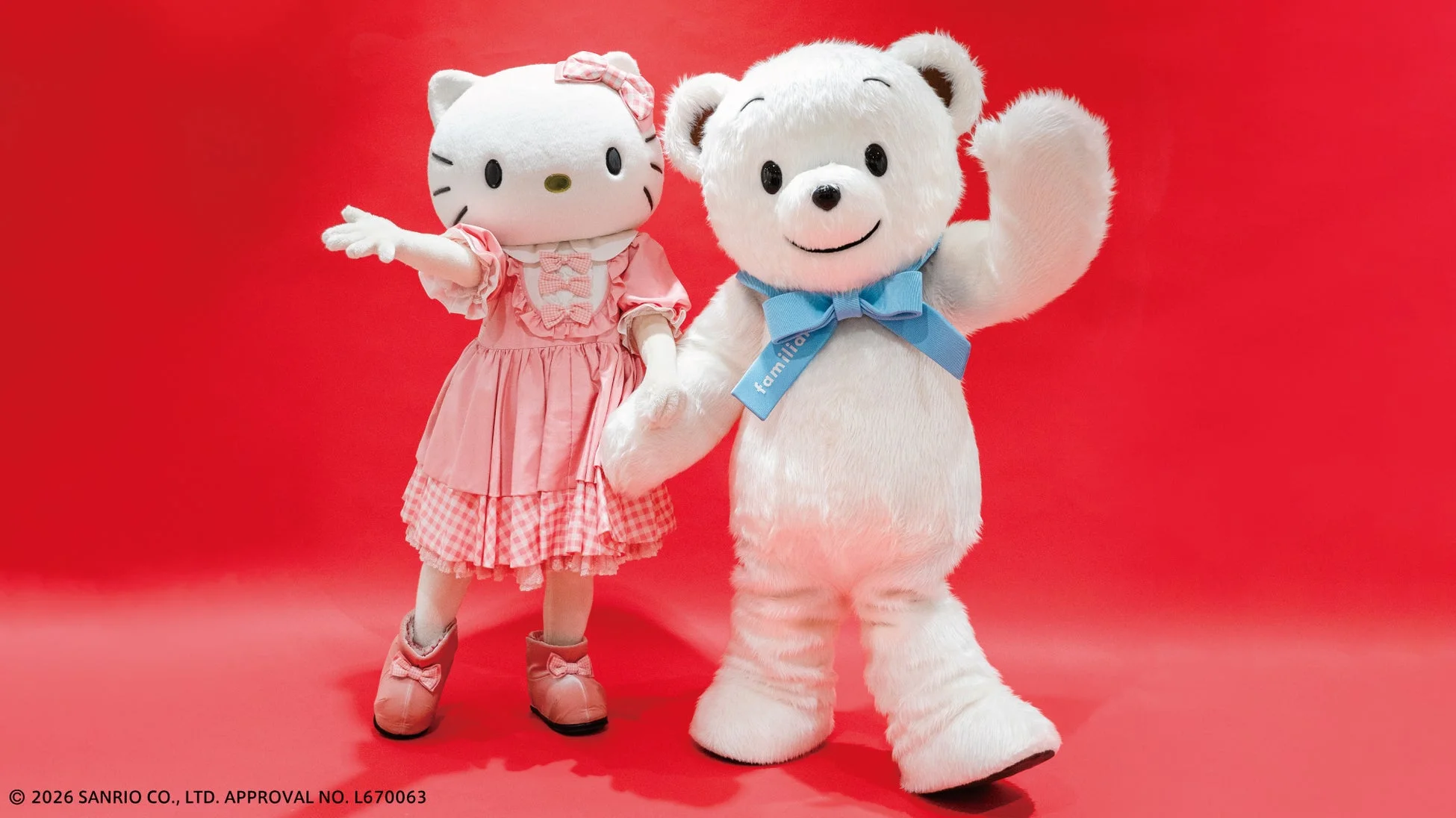 ハローキティと白いクマのキャラクターが赤い背景の前で並んで立っています