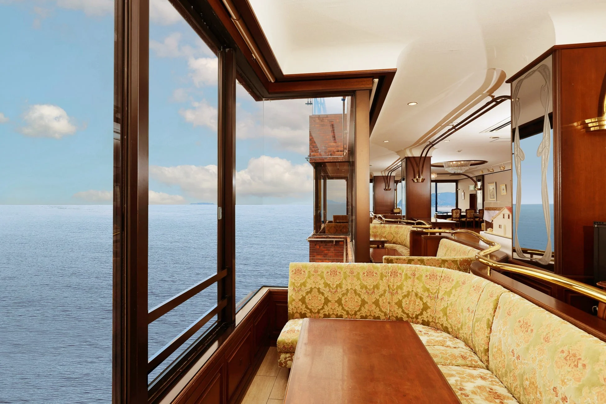 海に面した窓から壮大なオーシャンビューが広がる、豪華な内装のレストランまたはラウンジです。落ち着いた雰囲気のソファ席が並び、リラックスできる空間を提供しています。