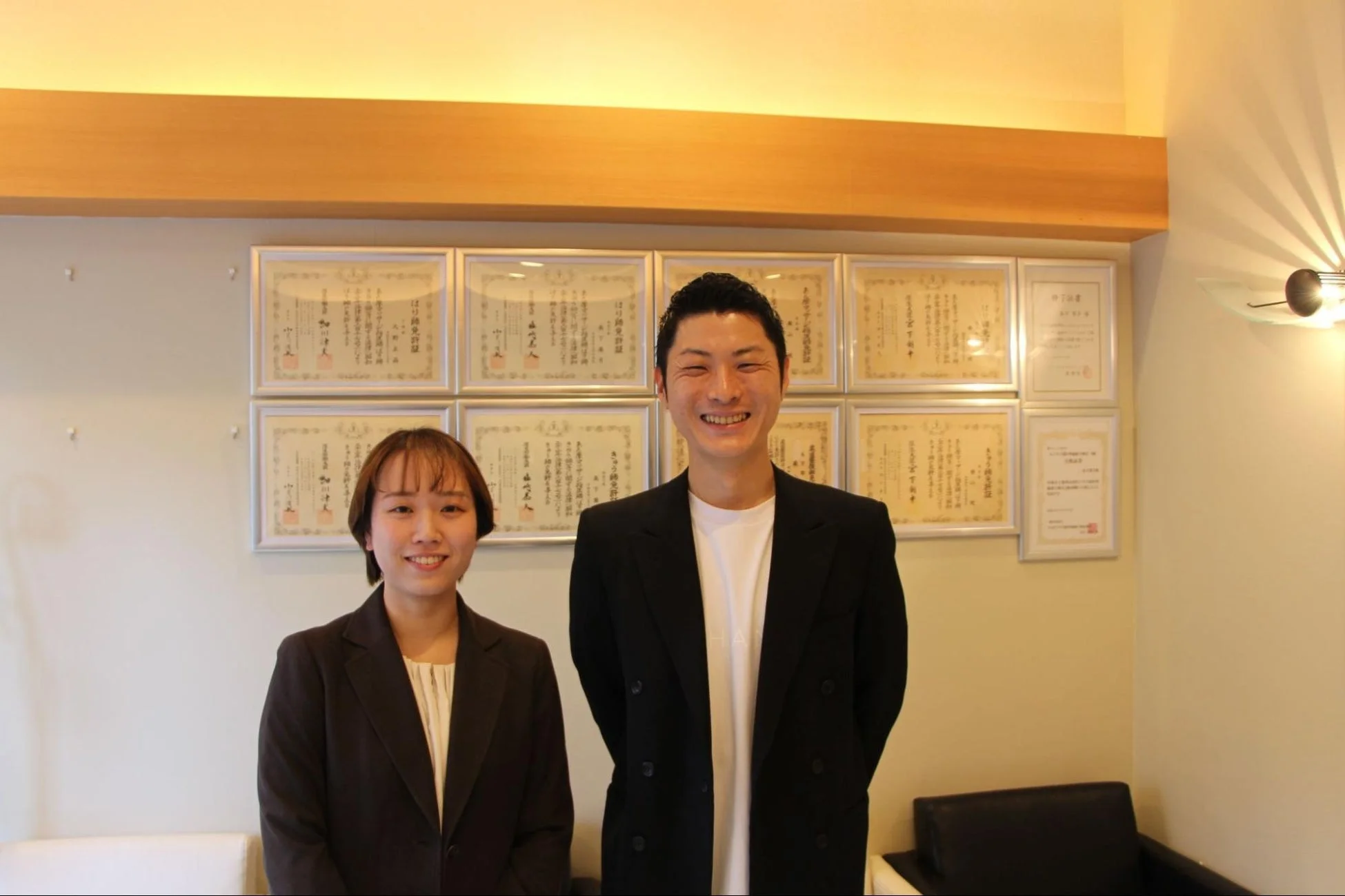 ブレイシング社の担当者2名と壁に飾られた免許証
