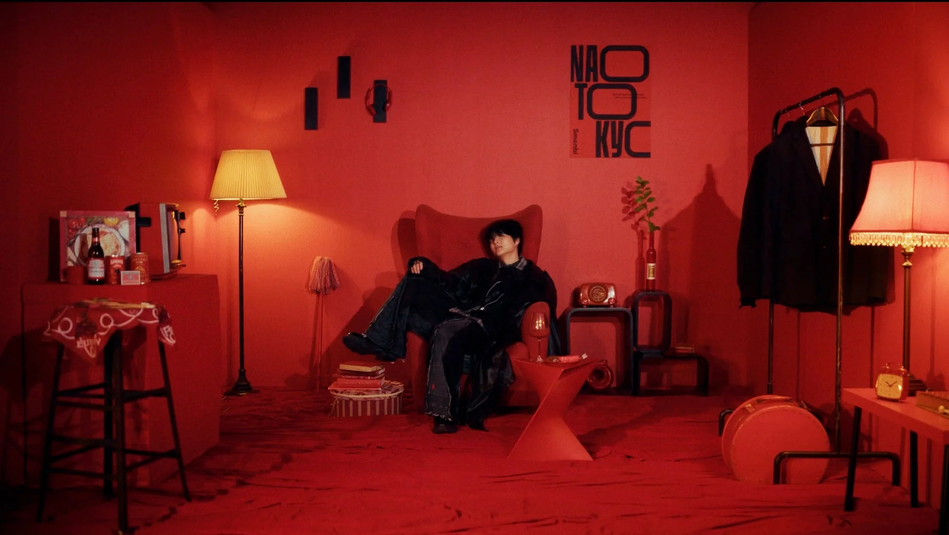 赤い部屋全体が赤で統一された空間で、一人の男性がアームチェアに座ってくつろいでいます。部屋にはヴィンテージ風の家具や小物が配置され、独特の雰囲気を作り出しています。