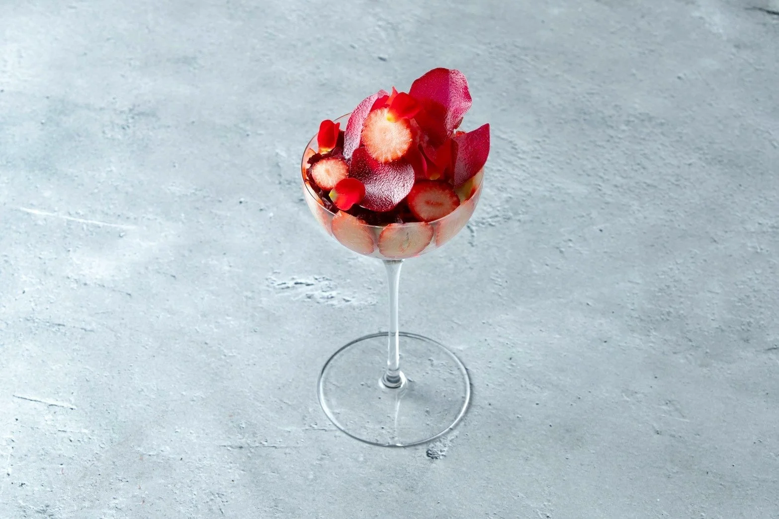 薄切りいちごと赤い花びらが美しく盛り付けられたグラスデザート