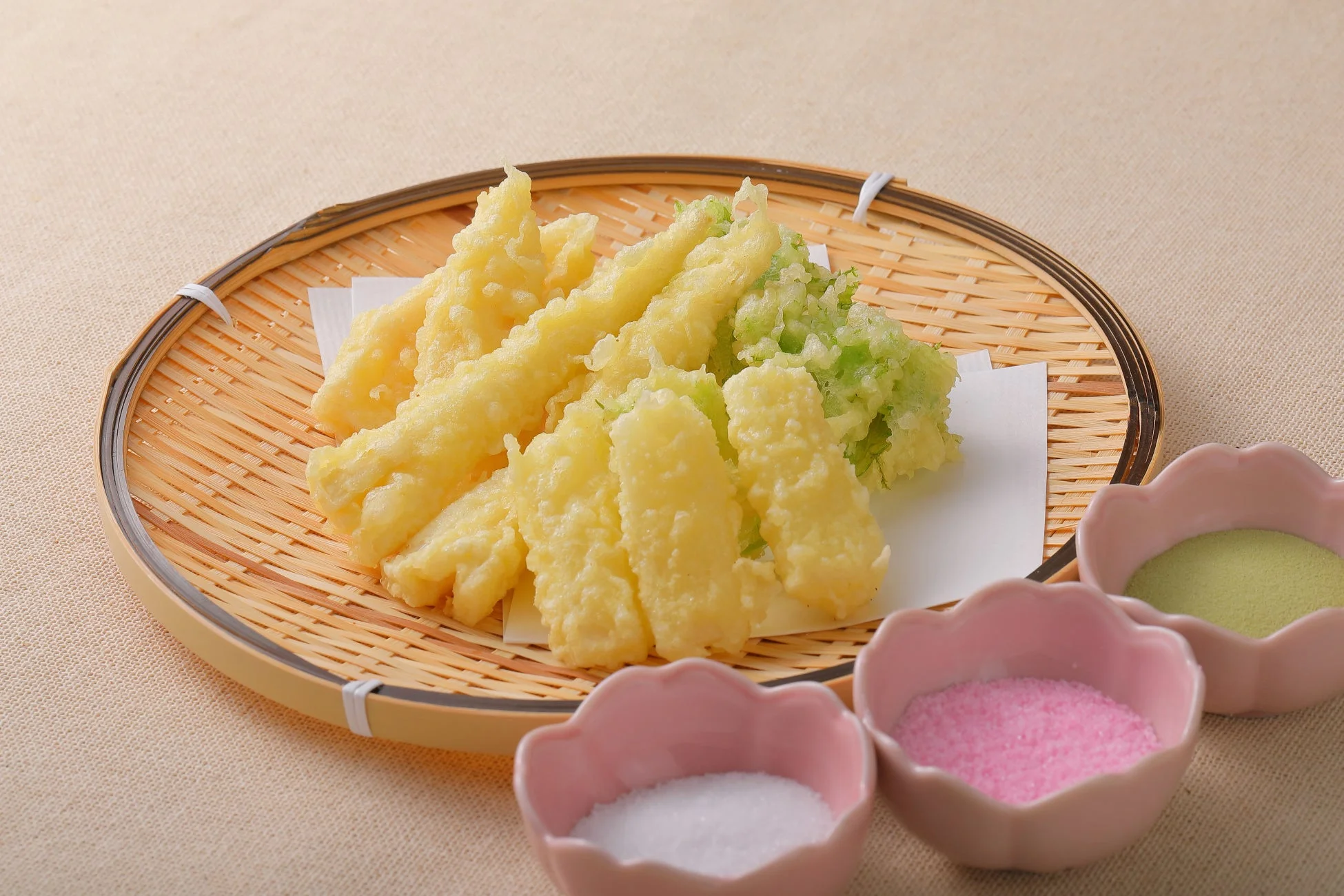 竹ざるに盛り付けられた天ぷらと、白、ピンク、抹茶色の3種類の塩が並んでいます。
