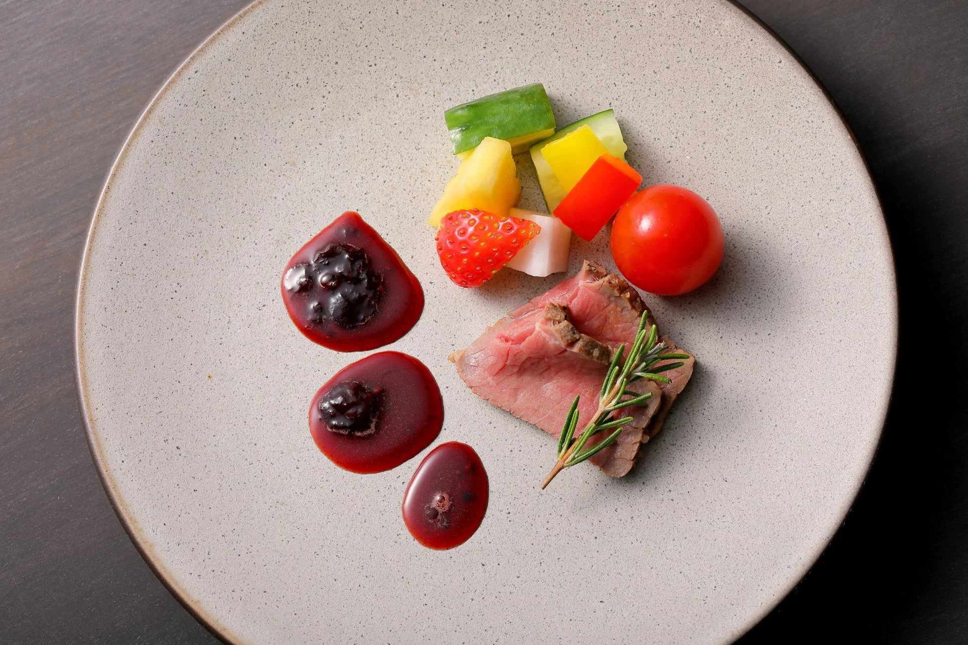 薄切りのローストビーフにローズマリーが添えられ、ミニトマト、キュウリ、パプリカ、イチゴ、パイナップルなどの彩り豊かな野菜とフルーツが盛り付けられた美しい一皿。