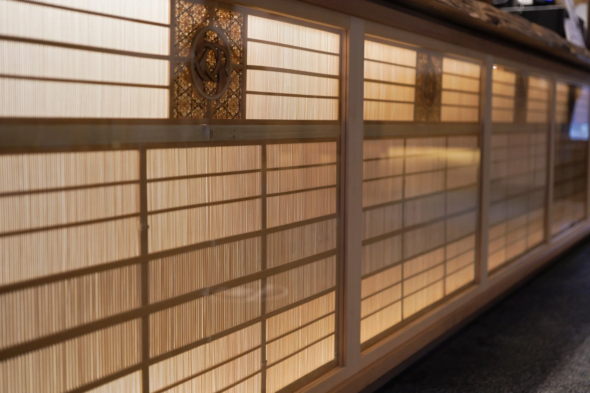 伝統的な日本の障子のような木製格子戸のクローズアップ。柔らかな光が透過し、温かみのある雰囲気を醸し出している。