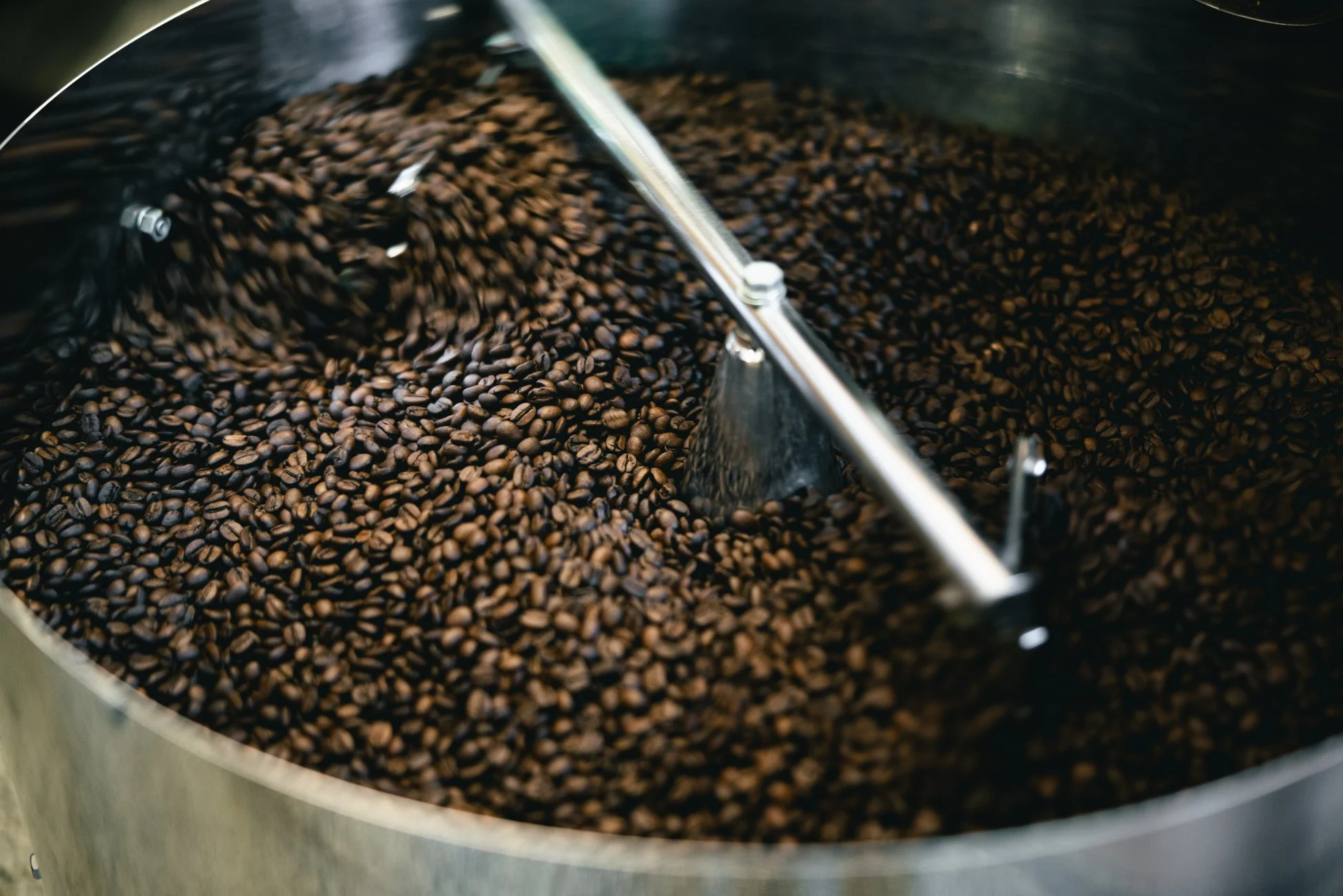 焙煎されたばかりのコーヒー豆が、金属製の機械の中で攪拌されながら冷却されている様子