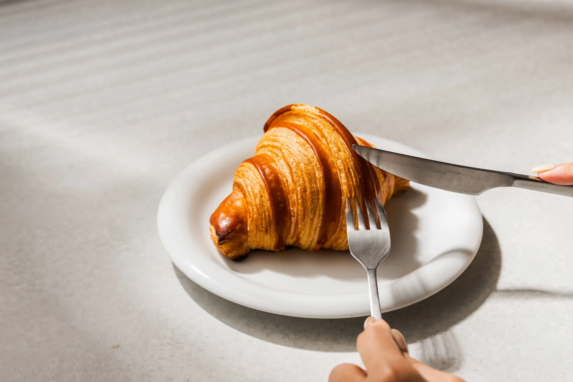ナイフとフォークが添えられた焼きたてのクロワッサン