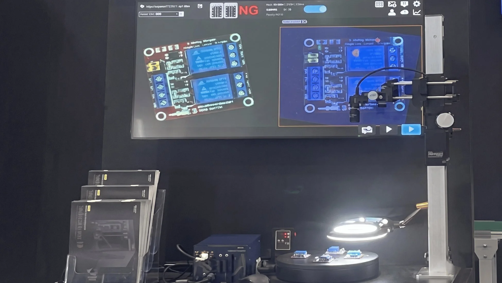 電子基板のリレーモジュール検査装置の展示風景。ディスプレイには検査対象の基板詳細と「NG」の表示があり、品質問題を示唆。手前では回転台上の電子部品が拡大鏡で精密に検査されています。