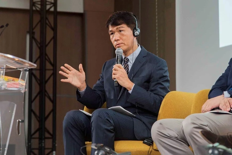 スーツ姿でマイクを持つ井上岳久氏