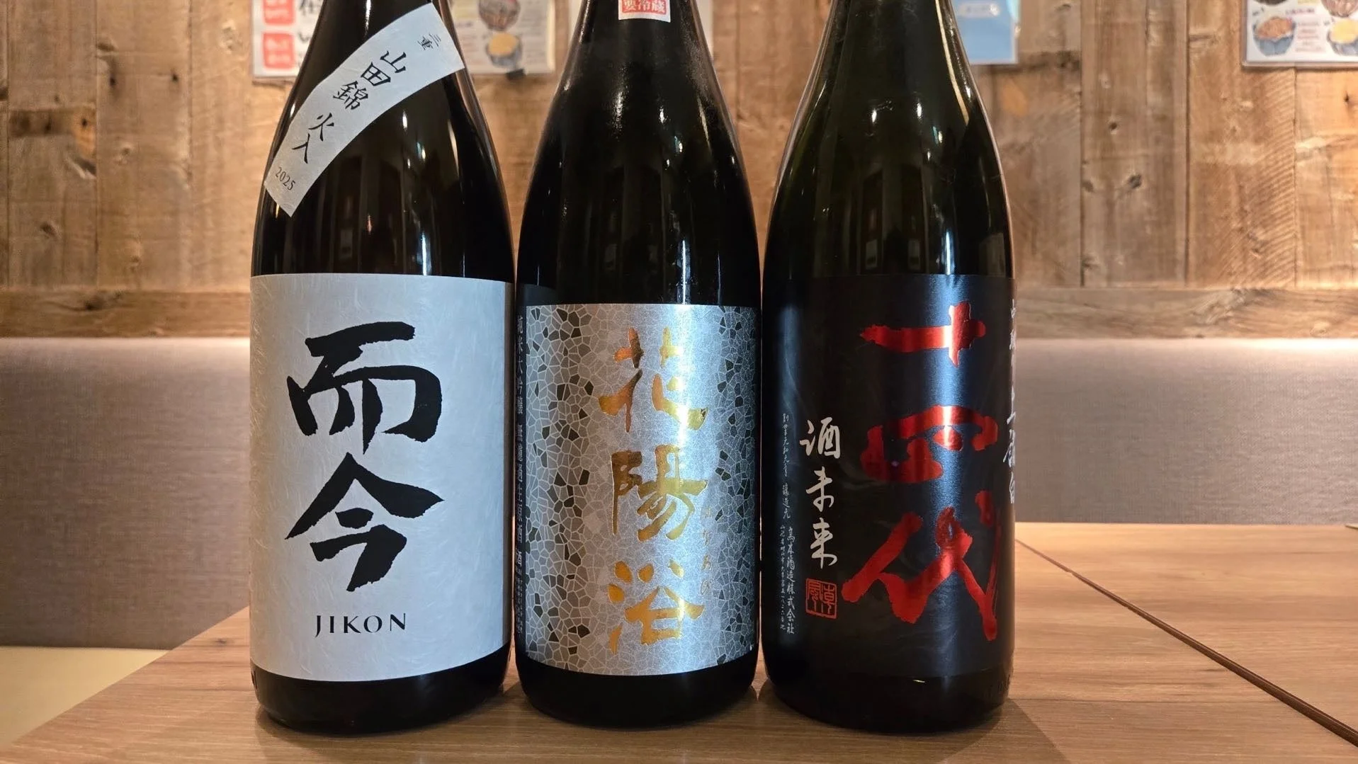 木製のテーブルに並べられた3本の日本酒のボトル