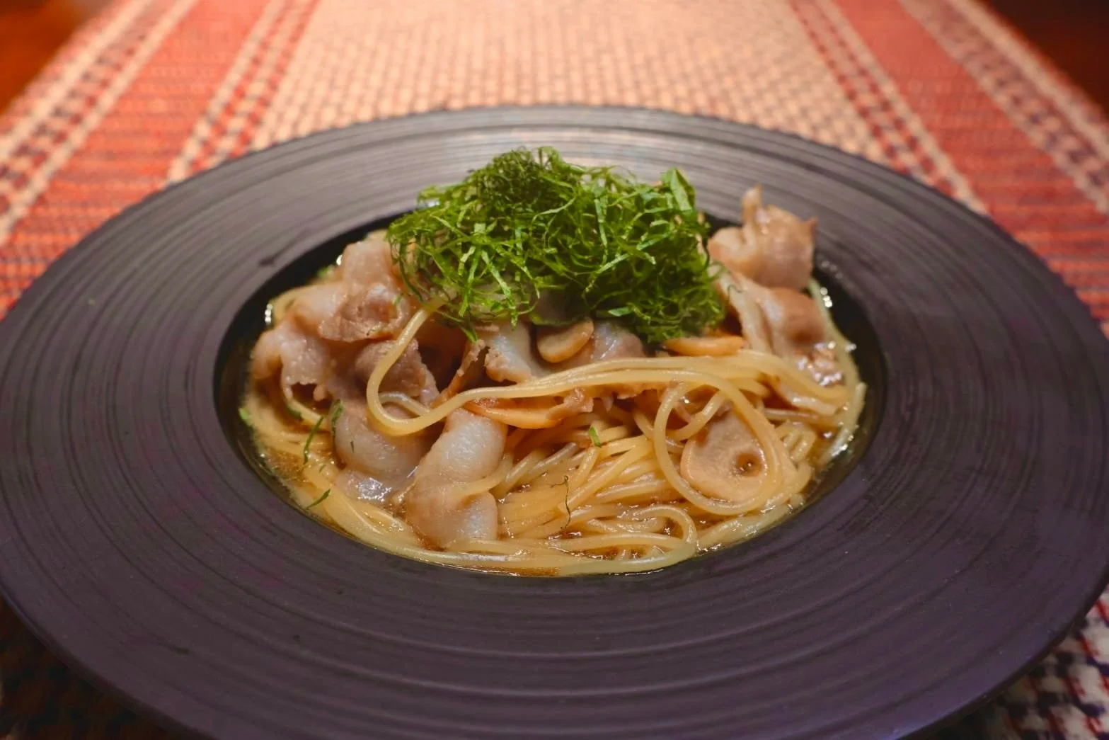 黒い深皿に盛られた豚しゃぶと梅のパスタ