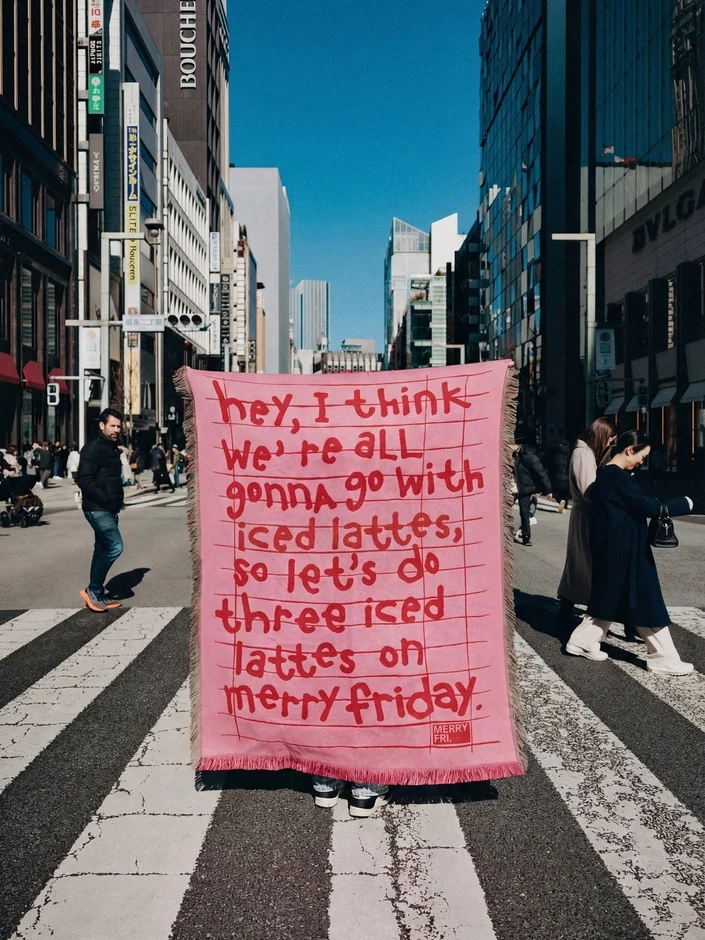 MERRYFRIDAYのピンクのブランケットを掲げる人物