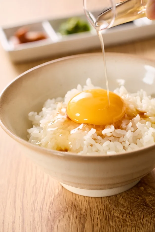 卵かけご飯に醤油をかける様子