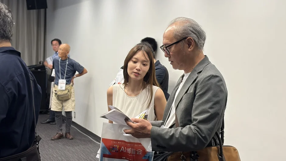 展示ブースで資料を見ながら話す来場者と出展者