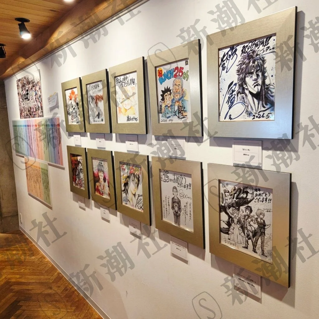白い壁のギャラリーに額装された漫画イラストが多数展示されている。人気漫画「北斗の拳」や「アルスラーン戦記」のキャラクター作品があり、25周年を記念した展示のようだ。サインや日付も見られ、新潮社のウォーターマークがある。