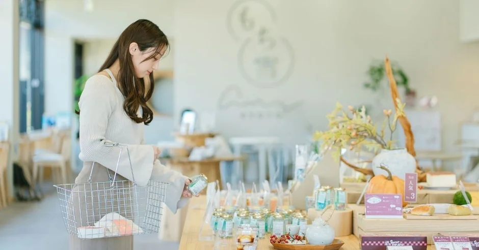 明るくモダンな店内で、女性がショッピングバスケットを持ちながら、並べられた商品を見ている